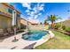 Backyard pool with rock features, a palm tree, seating and an umbrella on a sunny day at 1560 E Flint St, Chandler, AZ 85225