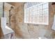 Updated shower showcases travertine tile, glass block window, and a handheld shower head at 15774 W Indianola Dr # Six, Goodyear, AZ 85395