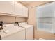This laundry room offers a washer and dryer, storage cabinets, and a window for natural light at 17323 E Teal Dr, Fountain Hills, AZ 85268