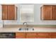 Close-up of the kitchen sink and granite counter with wood cabinets above and below at 18475 N Madison Rd, Maricopa, AZ 85139
