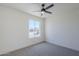 This bedroom features neutral carpet, white walls, a ceiling fan, and a view of the street at 2338 E Folley St, Chandler, AZ 85225