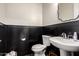 Stylish half bathroom with black wainscoting, white walls, and a pedestal sink at 25875 S 227Th Way, Queen Creek, AZ 85142