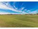 Expansive grassy field with a clear blue sky and distant mountains, perfect for outdoor activities and community events at 25875 S 227Th Way, Queen Creek, AZ 85142