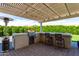 Outdoor kitchen with built-in grill, bar seating, and a covered pergola for shade at 25875 S 227Th Way, Queen Creek, AZ 85142