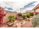 Unique backyard water feature surrounded by colorful flowers and lush greenery at 2926 N 149Th Dr, Goodyear, AZ 85395
