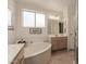 Well-lit bathroom featuring a soaking tub, bright window, and spacious vanity at 2926 N 149Th Dr, Goodyear, AZ 85395
