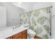 Cozy bathroom showcasing wooden vanity with sink, leafy-patterned shower curtain, and toilet at 4204 S Winter Ln, Gilbert, AZ 85297