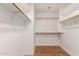 Walk-in closet with wood floors and white shelving and hanging rods for optimal storage and organization at 705 W Country Estates Ave, Gilbert, AZ 85233