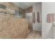 Walk-in shower featuring stone tile, glass door, shower head, and built-in shelving at 705 W Country Estates Ave, Gilbert, AZ 85233
