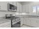 Stylish kitchen featuring stainless steel appliances, granite countertops, and white cabinetry at 9303 W Oregon Ave, Glendale, AZ 85305