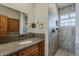 Neutral toned bathroom featuring granite countertops, wood cabinets, and a tiled walk-in shower at 9466 E Laurel Ln, Scottsdale, AZ 85260