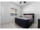 Simple bedroom with a dark upholstered bed, neutral walls, tile floors, and ceiling fan at 1330 E Monte Way, Phoenix, AZ 85042
