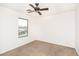 This carpeted bedroom features a modern ceiling fan and a sunlit window at 15028 W Columbine Dr, Surprise, AZ 85379