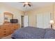 Cozy bedroom featuring neutral walls, ceiling fan, closet and wooden dresser with mirror and tv at 15288 W Redfield Rd, Surprise, AZ 85379