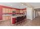 Bright kitchen with wooden cabinets, stainless steel appliances, red accent wall, and an island with barstool seating at 15288 W Redfield Rd, Surprise, AZ 85379