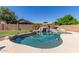 Lush backyard pool showcasing a rock waterfall, putting green, and desert landscaping at 15288 W Redfield Rd, Surprise, AZ 85379