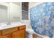 Full bathroom featuring wood vanity, a vanity mirror and decorative blue shower curtain at 16183 W Devonshire Ave, Goodyear, AZ 85395