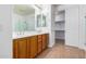 Bathroom with double sink vanity and walk-in closet featuring wood-look floors, white walls, and ample storage at 16183 W Devonshire Ave, Goodyear, AZ 85395