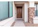 Beautifully carved wood front door framed by stone and a large window at 16183 W Devonshire Ave, Goodyear, AZ 85395