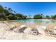 Sandy beach area near the community pool with lounge chairs and palm trees at 1633 E Lakeside Dr # 98, Gilbert, AZ 85234
