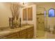 Bathroom with granite countertop, dual sinks, glass shower, and decorative elements exudes elegance and functionality at 16716 S 32Nd Ln, Phoenix, AZ 85045