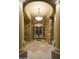 Impressive entryway with stone walls, marble floors, and decorative iron door, lit by a modern chandelier at 16716 S 32Nd Ln, Phoenix, AZ 85045