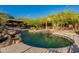 Luxurious backyard pool with rock features, stone patio, and a covered outdoor seating area at 16716 S 32Nd Ln, Phoenix, AZ 85045