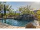 A backyard swimming pool area with a rock waterfall and desert plants at 16716 S 32Nd Ln, Phoenix, AZ 85045