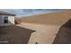 Unlandscaped backyard featuring dirt, a tall block wall, and partial view of the home's exterior at 18564 W Cathedral Rock Dr, Goodyear, AZ 85338