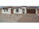 Charming single-story home with a desert-scape front yard, a brick driveway, and a two-car garage at 18564 W Cathedral Rock Dr, Goodyear, AZ 85338