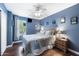 Blue bedroom with hardwood floors, a ceiling fan, and a window providing plenty of natural light at 1870 E Oakland St, Gilbert, AZ 85295