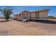 Exterior shot of a tan single story home with a front porch on a dirt lot with sparse vegetation at 22819 E Ray Rd, Mesa, AZ 85212