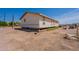 Low angle view of the back exterior of a tan colored single story home on a dirt lot at 22819 E Ray Rd, Mesa, AZ 85212