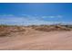 Dirt lot with sparse vegetation and piles of dirt with a blue sky overhead at 22819 E Ray Rd, Mesa, AZ 85212