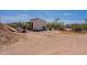 Outdoor shot of a dirt lot featuring an outbuilding, sparse landscaping, and blue sky at 22819 E Ray Rd, Mesa, AZ 85212