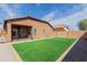 View of the backyard with artificial turf, rock landscaping, covered patio, and the home's exterior at 28072 N Quartz Dr, San Tan Valley, AZ 85143