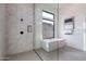 Elegant bathroom showcasing a modern tub, glass-enclosed shower, and marble tile accents with a large window at 28421 N 59Th Way, Cave Creek, AZ 85331