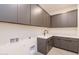 Functional laundry room with sleek cabinetry, a modern sink, and ample counter space for convenience and organization at 28421 N 59Th Way, Cave Creek, AZ 85331