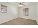 The spacious bedroom includes neutral carpeting and two windows with wood-look blinds and a ceiling fan at 2947 N Evergreen St, Buckeye, AZ 85396