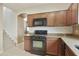 Traditional kitchen featuring tile floors, granite countertops, wood cabinets, and black appliances at 2947 N Evergreen St, Buckeye, AZ 85396