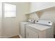 A bright laundry room with white appliances, a window, tile floors, and white walls at 2947 N Evergreen St, Buckeye, AZ 85396