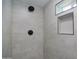 Modern shower featuring gray tiled walls, black fixtures, and built-in shelving with black trim at 3249 E Sunnyside Ln, Phoenix, AZ 85032
