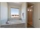 Relaxing bathroom featuring a large soaking tub, a window with neighborhood views and a tiled shower at 3574 E Glacier Pl, Chandler, AZ 85249
