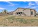 Expansive backyard with patio, lush lawn, a desert landscape and a decorative sun emblem on the home's exterior at 43271 W Little Dr, Maricopa, AZ 85138