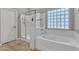 Bright bathroom features a soaking tub, glass-enclosed shower, and tiled floors at 43271 W Little Dr, Maricopa, AZ 85138