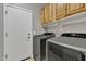 Convenient laundry room with modern washer, dryer, wooden cabinets, and access to the exterior at 43271 W Little Dr, Maricopa, AZ 85138