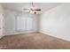 Spacious bedroom features neutral carpet, ceiling fan, and bright window at 44574 W Garden Ln, Maricopa, AZ 85139