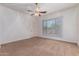 Bright bedroom featuring neutral carpet, ceiling fan and a view to the exterior at 44574 W Garden Ln, Maricopa, AZ 85139