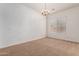 Bright, airy living room with neutral carpet, white walls, and a classic chandelier at 44574 W Garden Ln, Maricopa, AZ 85139