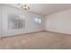 Spacious, carpeted living room illuminated by natural light, with a decorative chandelier at 44574 W Garden Ln, Maricopa, AZ 85139